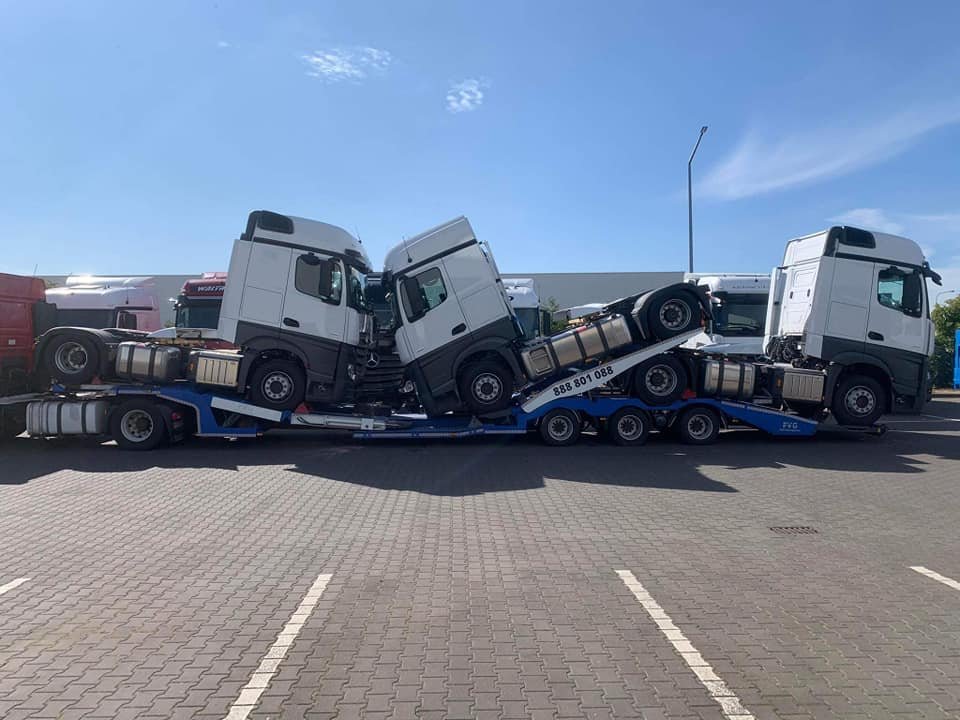 Transport lawetą trzech białych ciężarówek marki Mercedes.